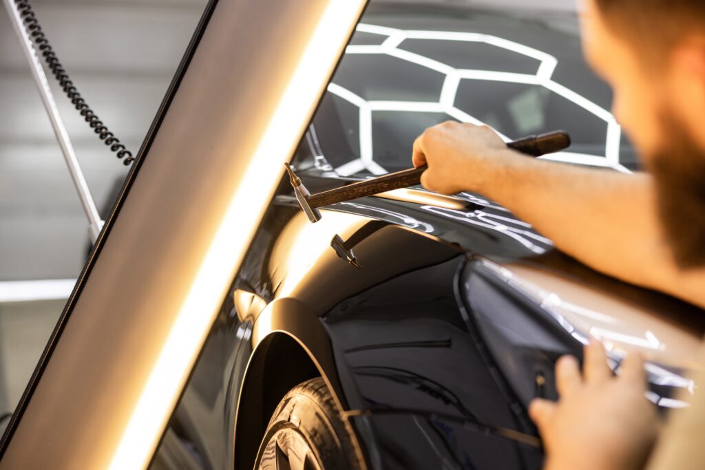Technician repairing hail damage on a car panel in the Bailey Smash Repairs workshop